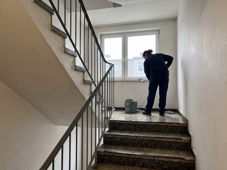 Treppenhausreinigung in einem Mehrfamilienhaus, die Terrazzostufen werden feucht gewischt